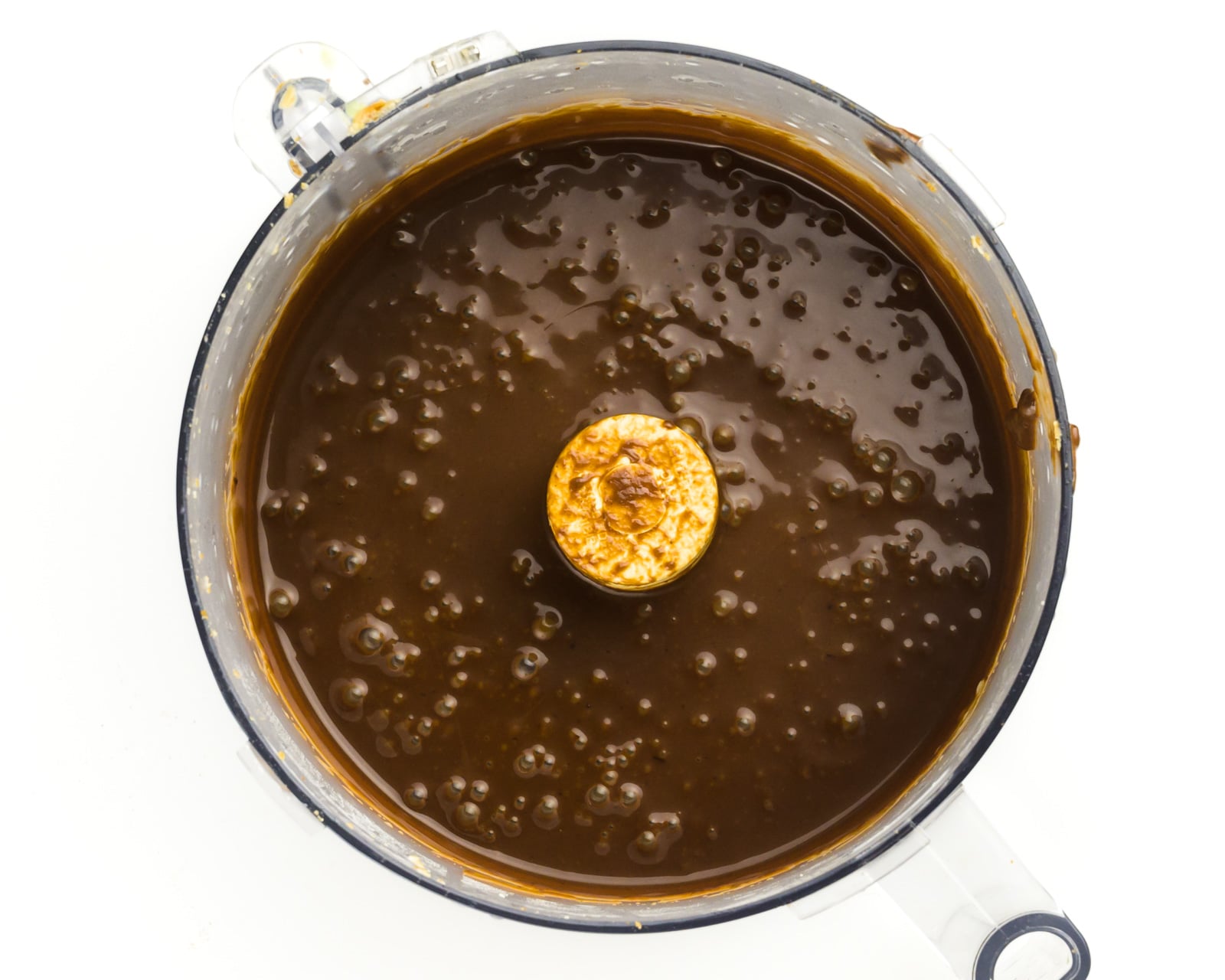 Chocolate sauce is in the bottom of a food processor bowl.