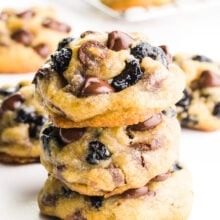 A stack of blueberry chocolate chip cookies sits in front of more cookies in the background.