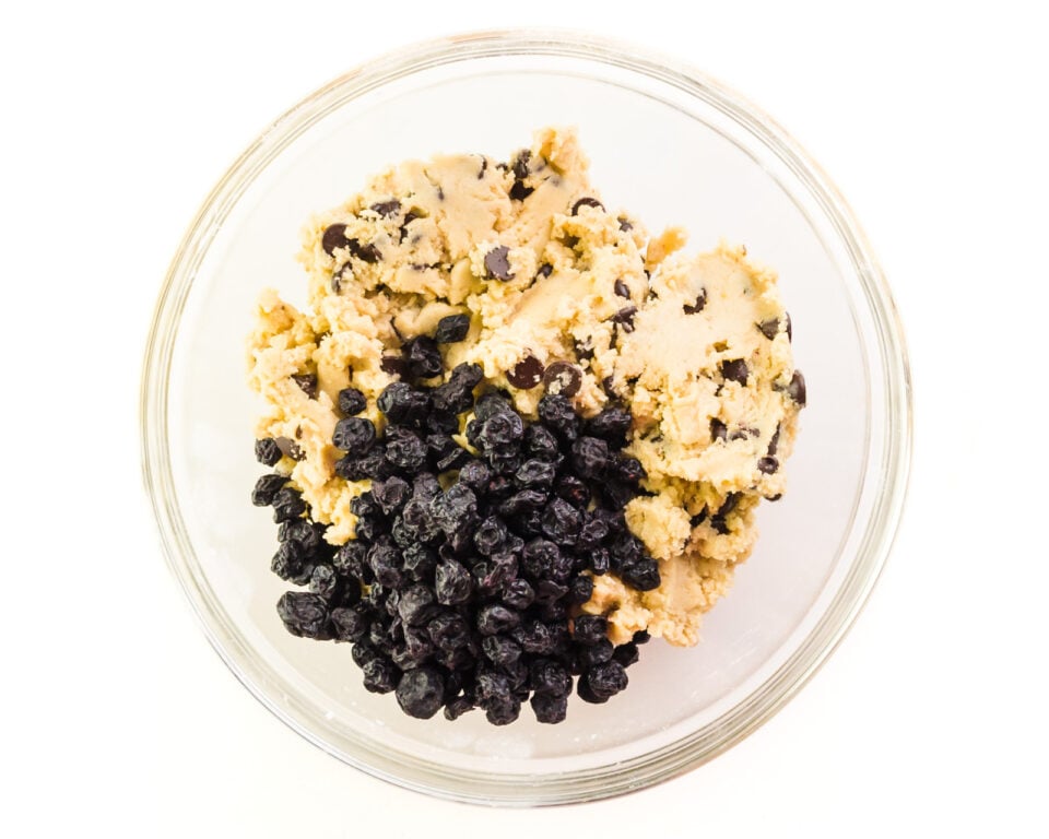Looking down on a bowl full of cookie dough with dried blueberries in it.