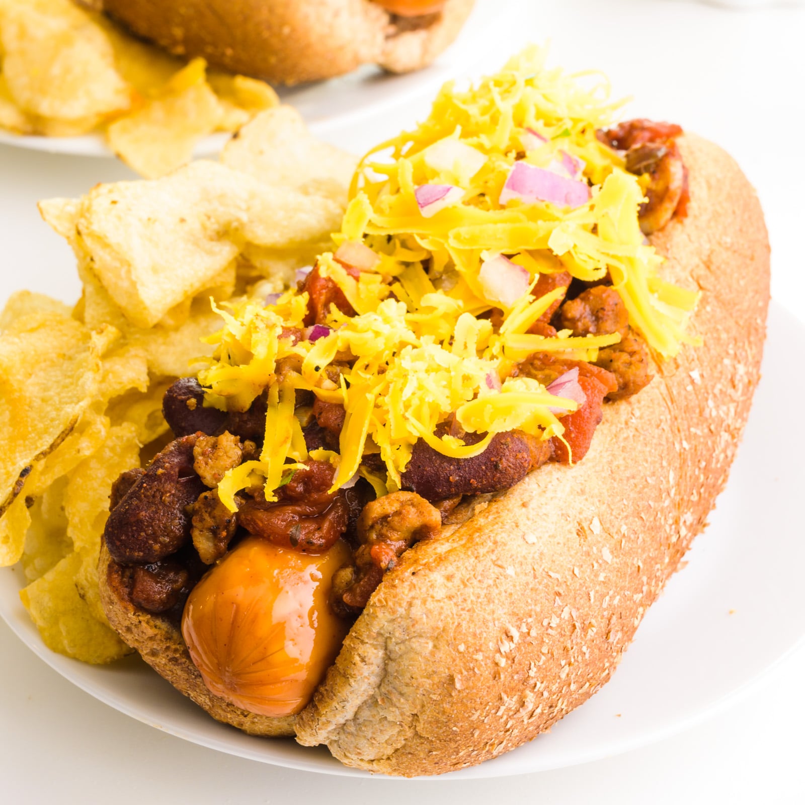 A vegan chili dog on a bun with vegan cheese on top.