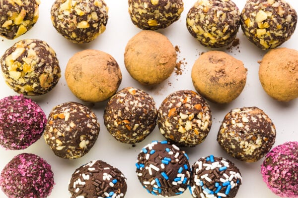 Looking down on several rows of vegan truffles, all with different toppings, like nuts or sprinkles.