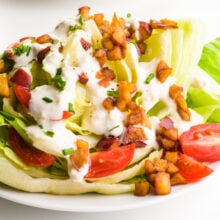 A close-up of a vegan wedge salad, with tomatoes, dressing, and smoky apple bits.