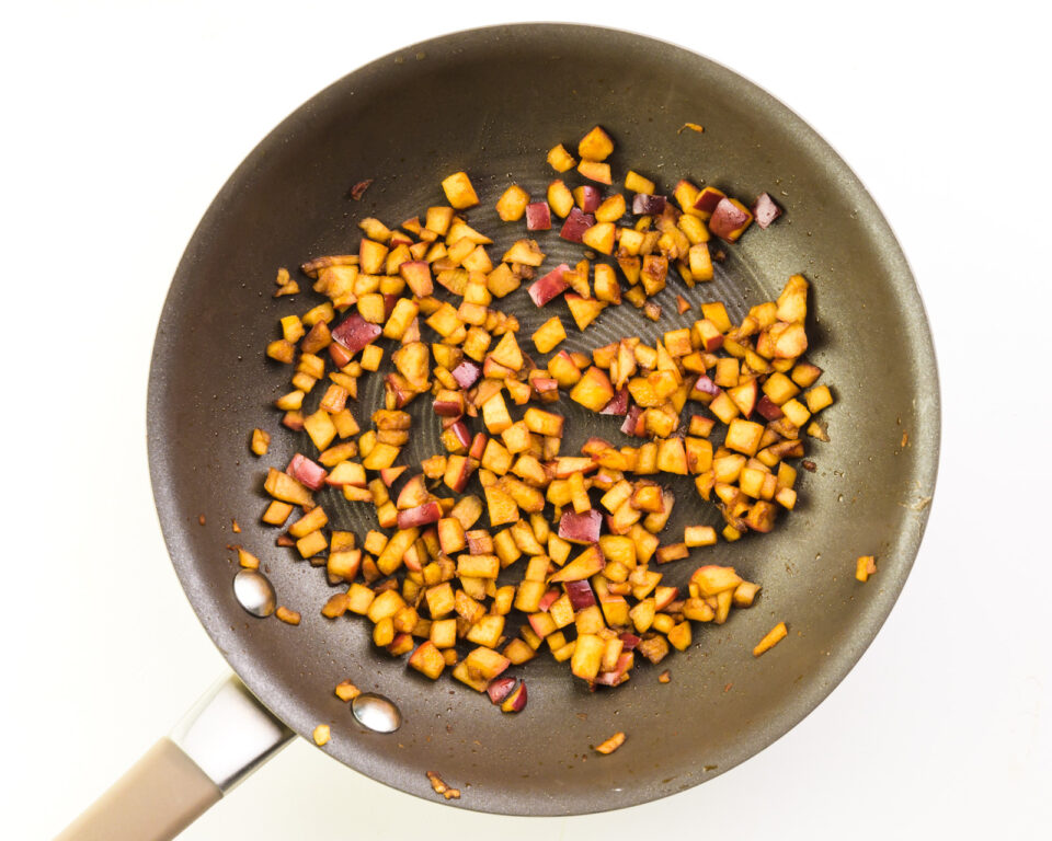Bits of apple are in the bottom of a skillet. They're lightly browned from cooking and from the added smoke sauce.