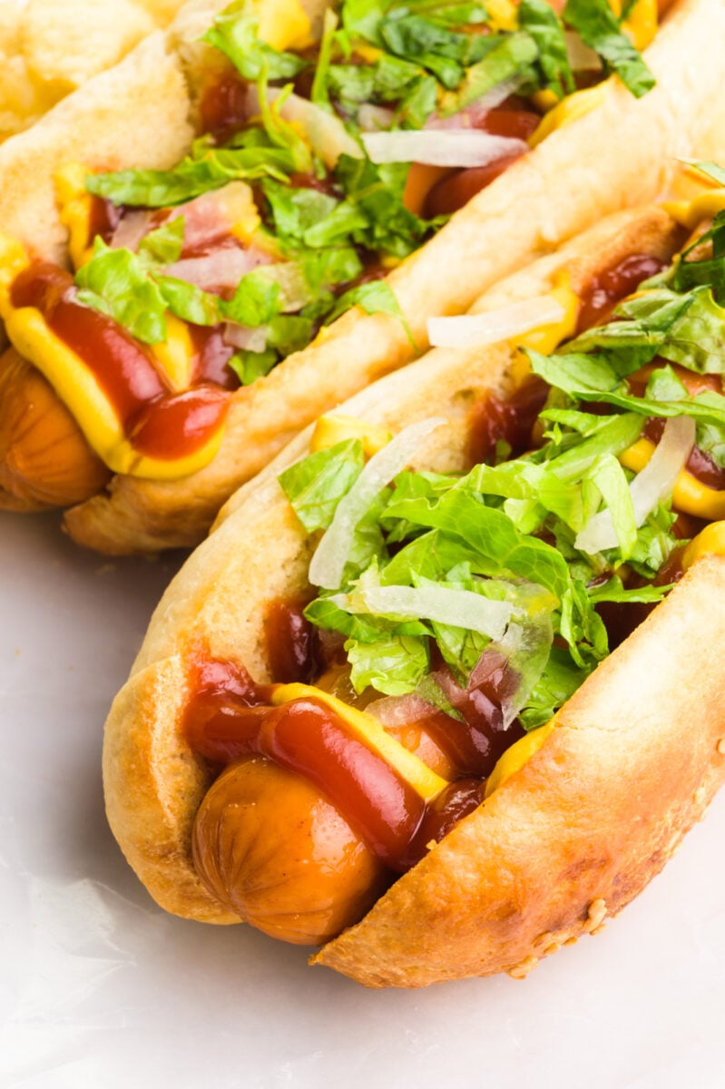 Two vegan hot dogs have hot dogs inside with toppings like ketchup and mustard.