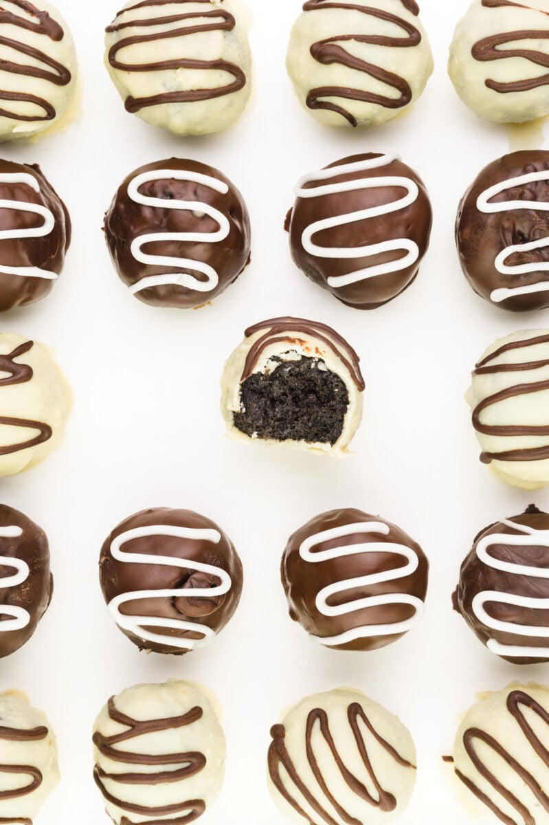 Looking down on several chocolate-covered Oreo Truffles, one with a bite taken out.