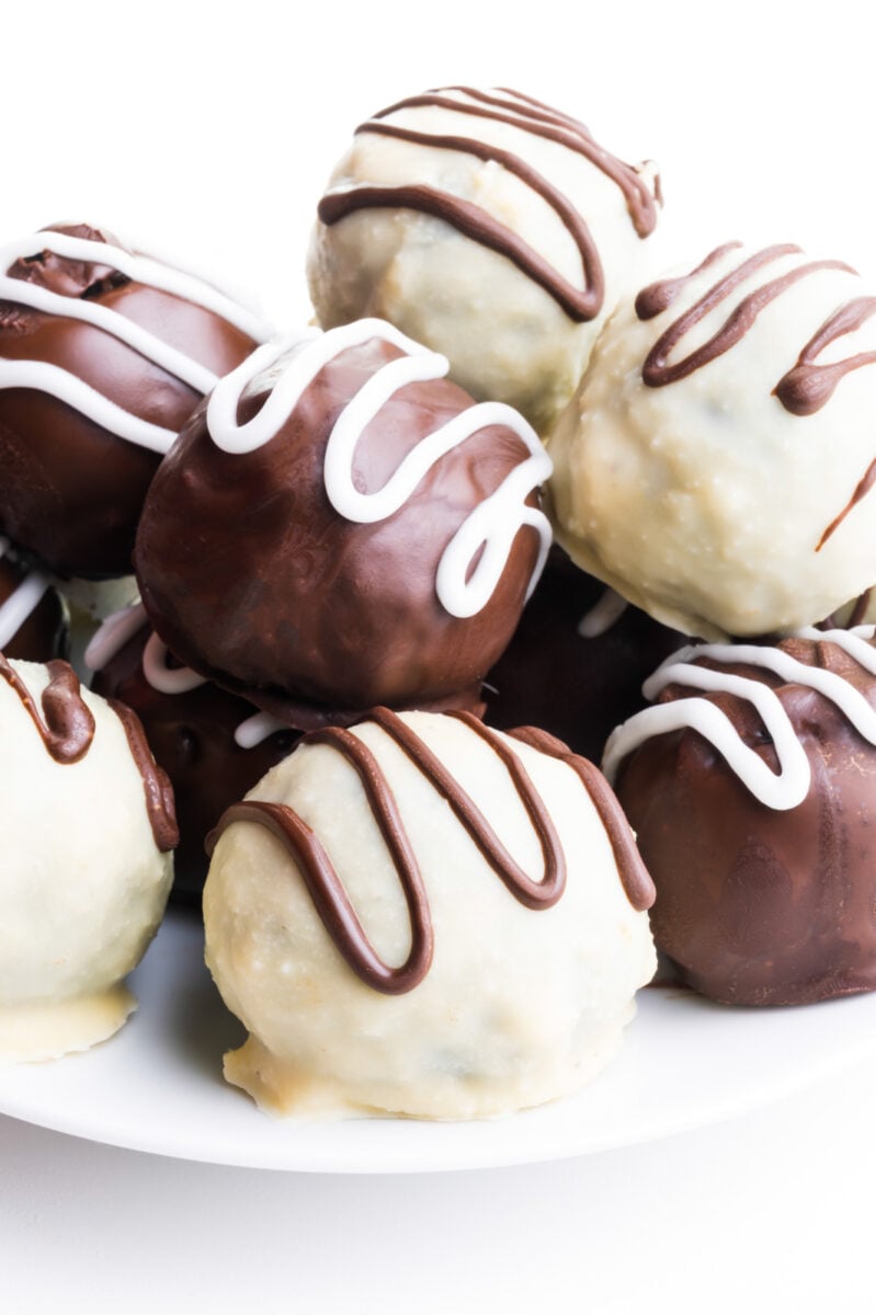 A pile of chocolate covered Oreo Truffles sits on a white plate.