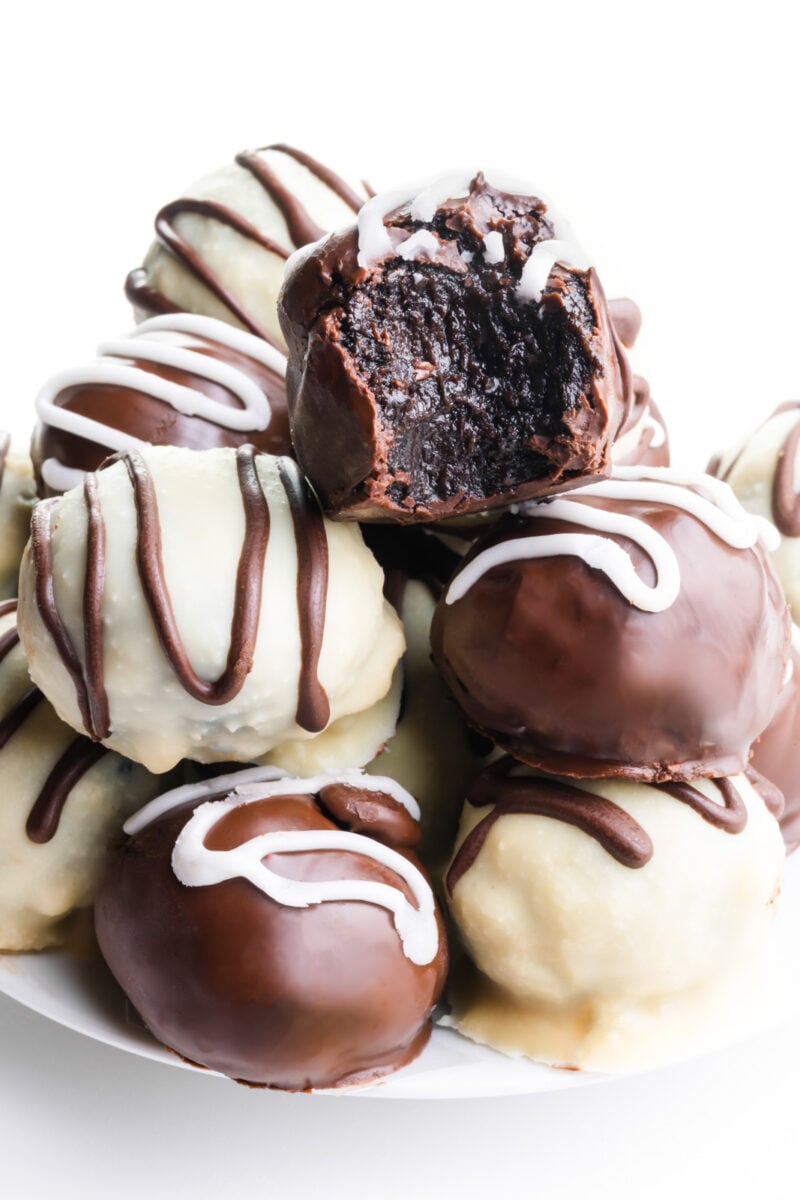A plate holds several chocolate candies, one with a bite taken out.