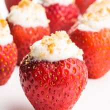 Vegan stuffed strawberries sit on a white counter. Each of them has graham cracker crumbs on top.