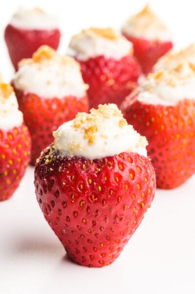 Vegan stuffed strawberries sit on a white counter. Each of them has graham cracker crumbs on top.