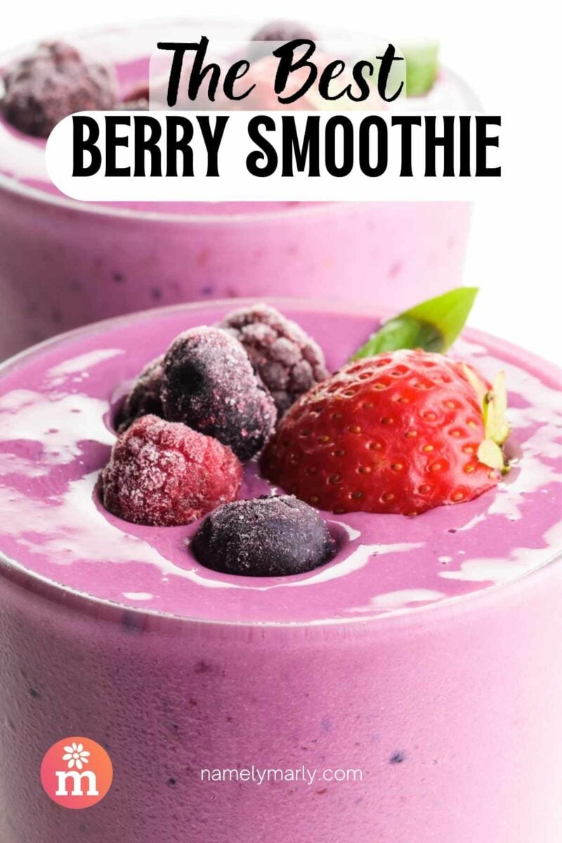 Purple berry smoothie topped with strawberries and mixed berries in a glass.