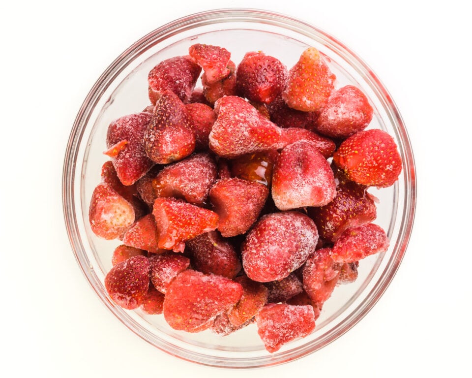 Looking down on a bowl full of frozen strawberries.