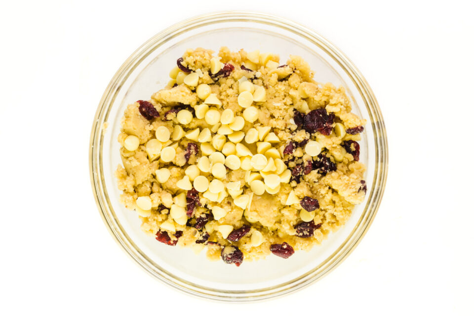 Looking down on a bowl of cookie dough with dried cranberries and white chocolate chips.