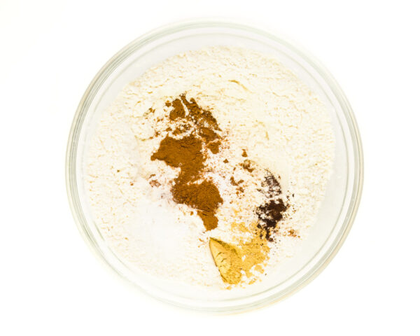 A bowl of flour has spices on top of it.