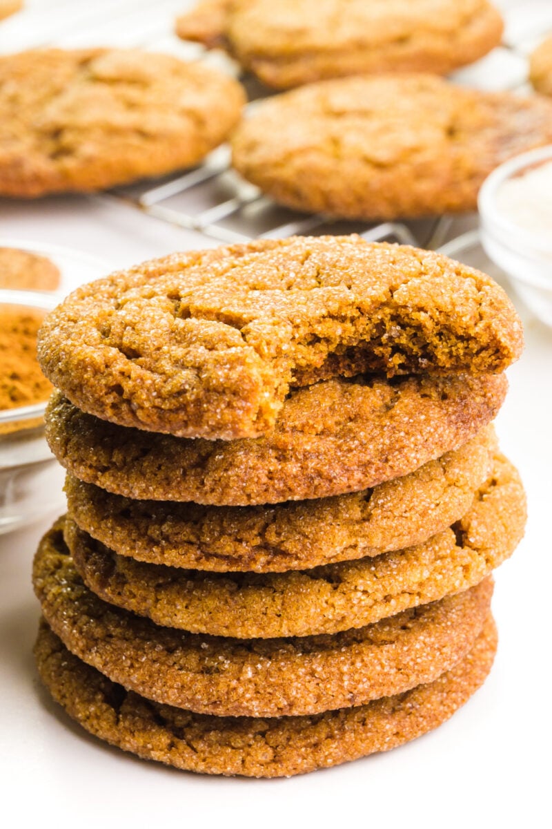 A stack of soft molasses cookie shows the top one with a bite taken out. There are more cookies behind the stack.
