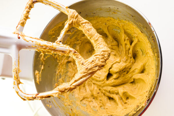 Looking down on a stand mixer with molasses cookie dough in the mixing bowl. The beater is also covered in cookie dough.