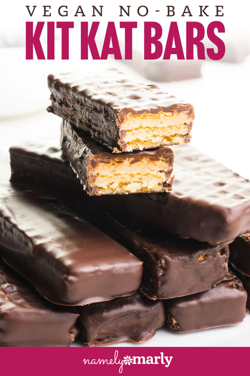 A stack of vegan Kit Kat Bars has two at the top that have been chopped in half, revealing the cookie underneath a chocolate coating. There are chocolate chips and more bars in the background. Text reads vegan no-bake kit kat bars.