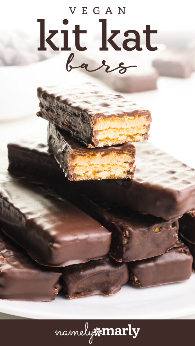 Stack of vegan Kit Kat bars, with one cut in half to display layers of crispy wafer and creamy filling.
