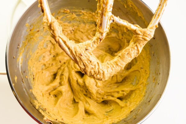 Looking down on a mixing bowl full of cookie dough. The beater is covered with cookie dough as well.