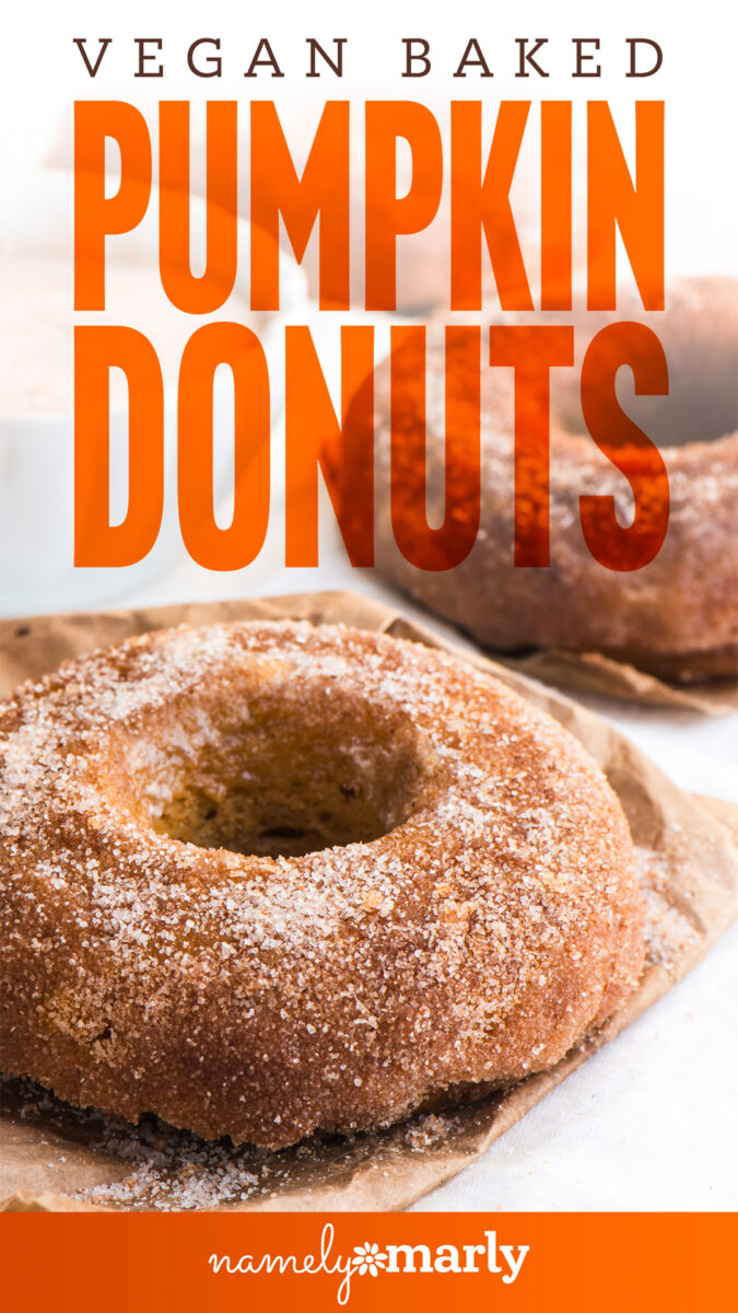 Vegan baked pumpkin donuts dusted with sugar on a brown paper background.