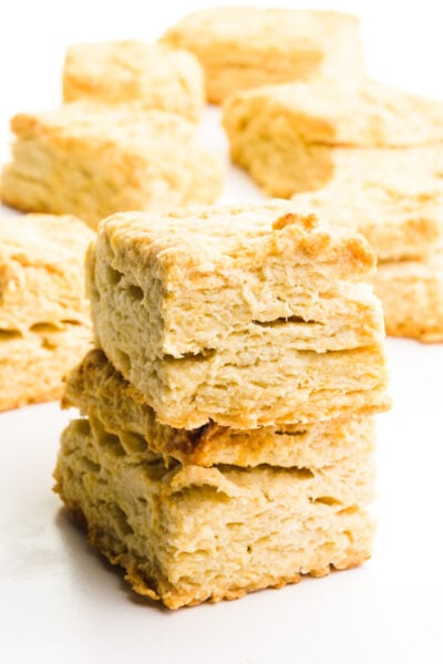 A stack of rectangle vegan biscuits sits in front of other biscuits in the background.