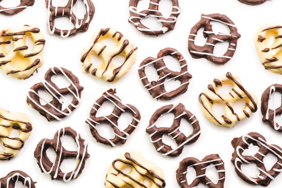 Looking down on a white counter with white and dark chocolate covered pretzels.