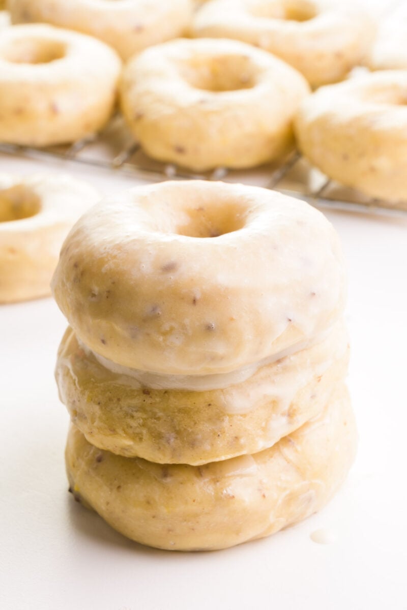 A stack of three air fryer donuts since in front of more donuts in the background.
