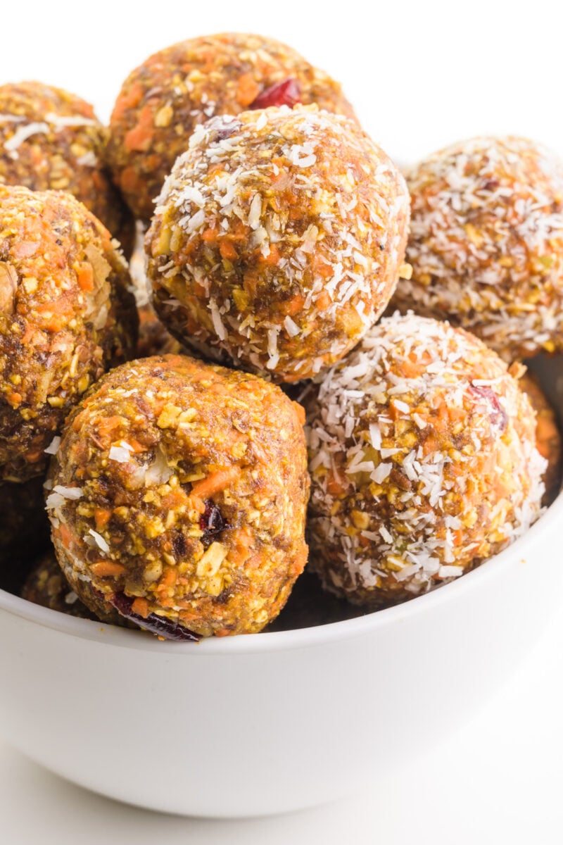 A bowl holds several healthy treats made from carrots and coconut flakes.