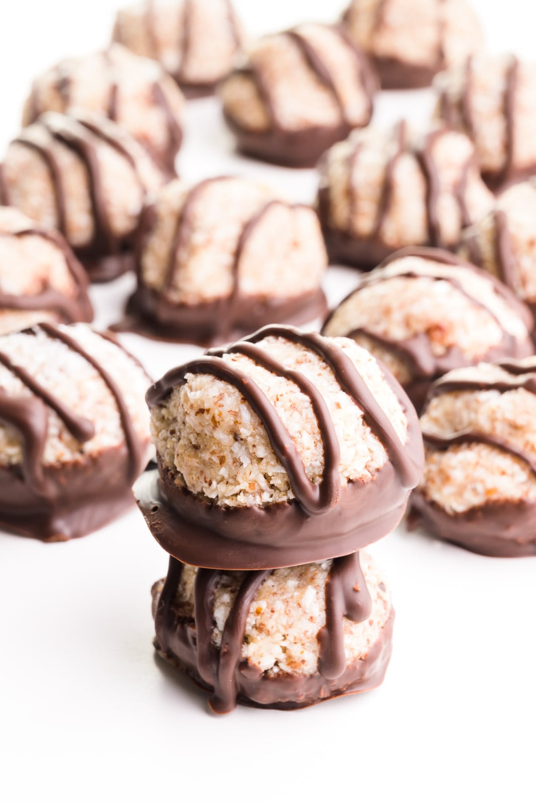 A stack of chocolate coconut macaroons has many more of the sweet treats behind it.