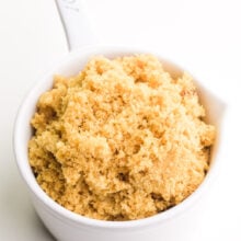 A white measuring cup holds homemade brown sugar.