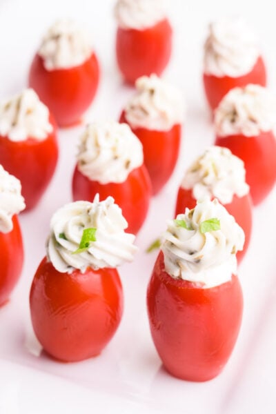 Looking down on an appetizer tray full of stuffed cherry tomatoes.