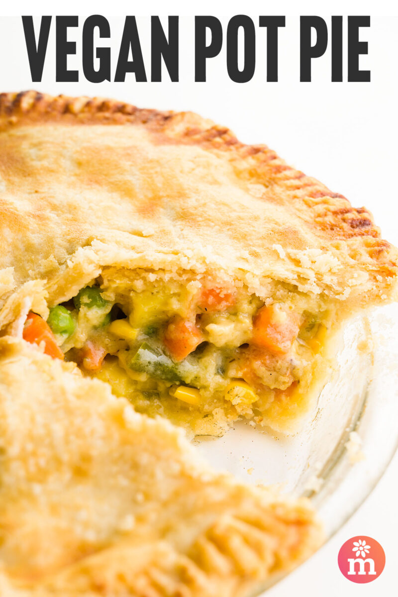 Vegan pot pie with a golden crust, filled with mixed vegetables and creamy sauce, showing a slice removed.
