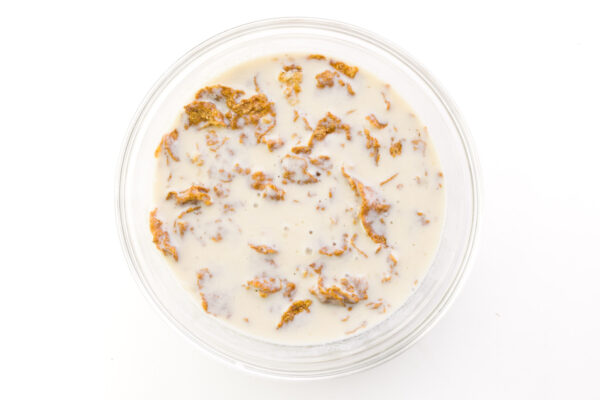 Bran cereal is surrounded by vegan buttermilk in a bowl.