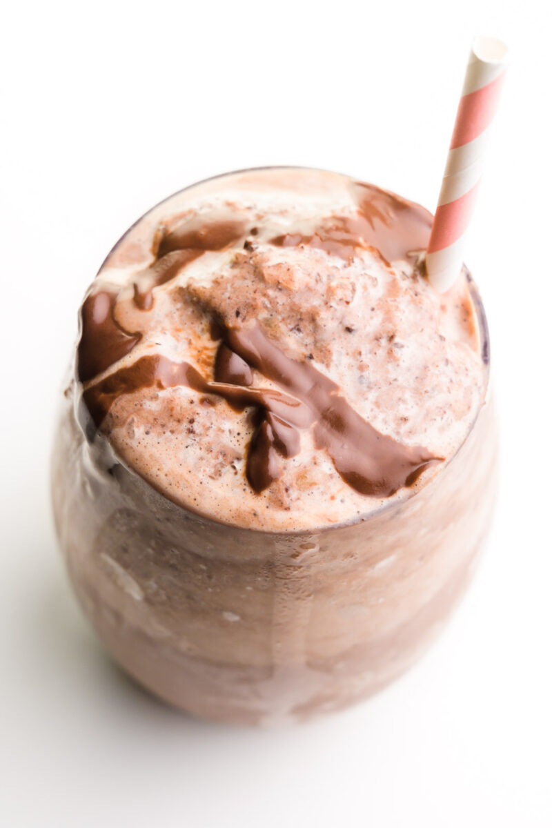 Looking down on a glass full of vegan chocolate milkshake with a pink straw on it.