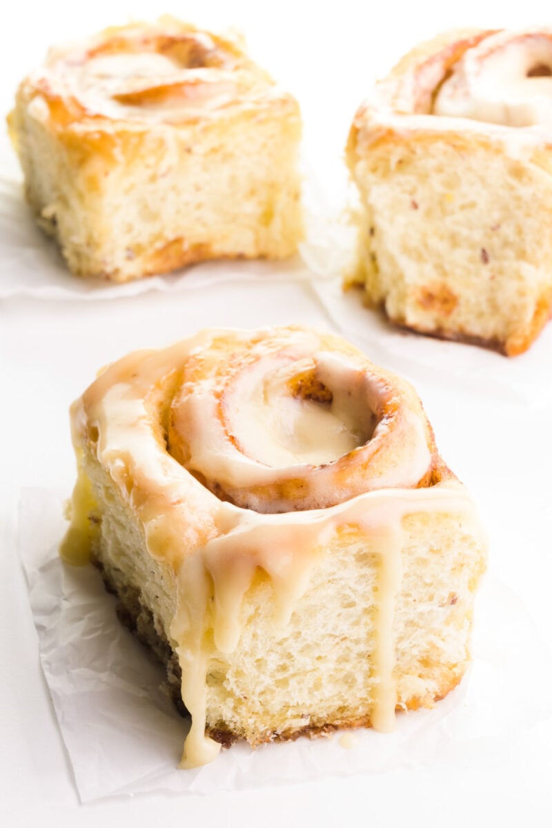 Three vegan cinnamon rolls are on a white counter.