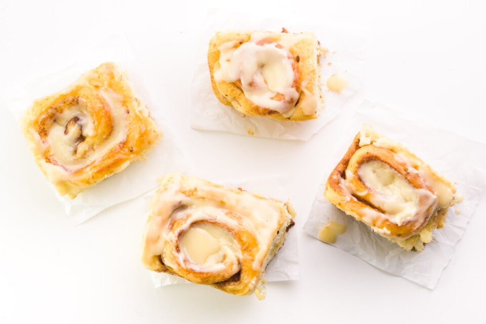 Looking down on four cinnamon rolls on a white counter.