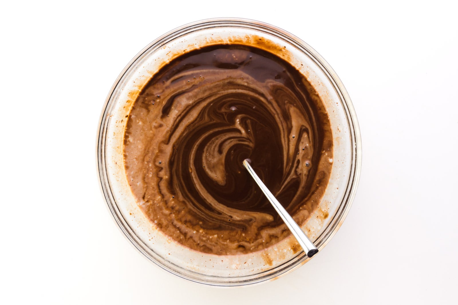 Looking down on a bowl full of vegan ganache, with a spoon used to stir it.