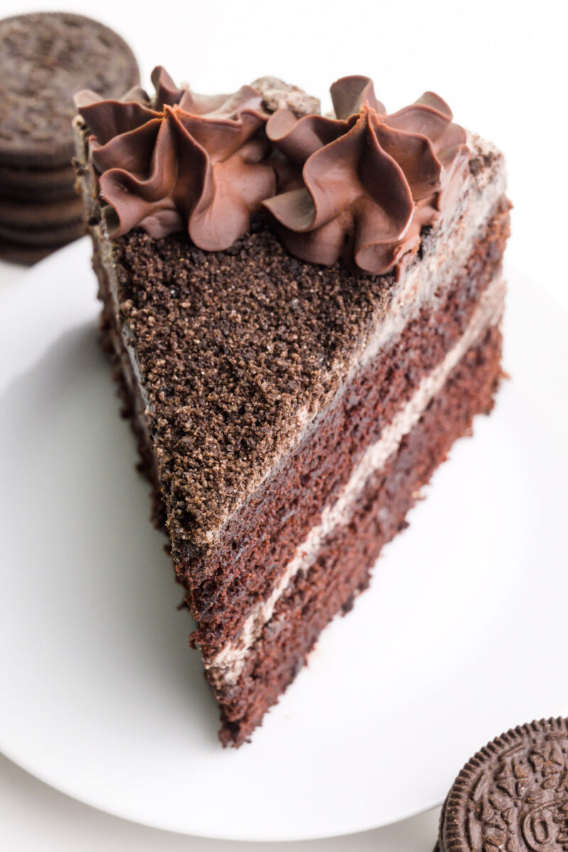 Looking down on cake covered with icing, cookie crumbs, and chocolate ganache.
