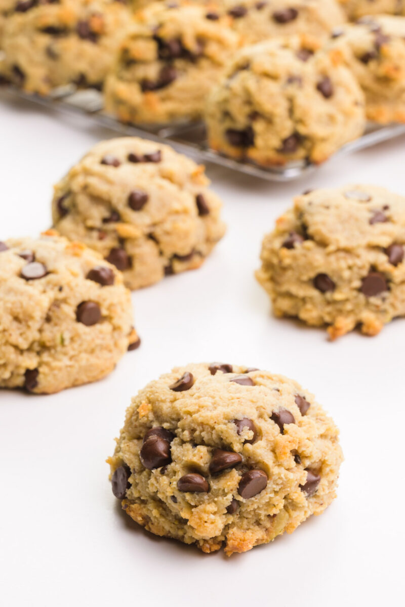 An almond chocolate chip cookie sits in front of more cookies in the background.