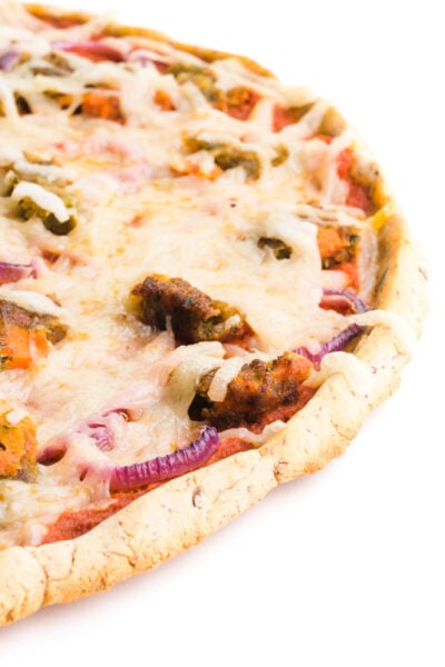A cassava flour pizza crust has toppings like red sauce and cheese on top of it.