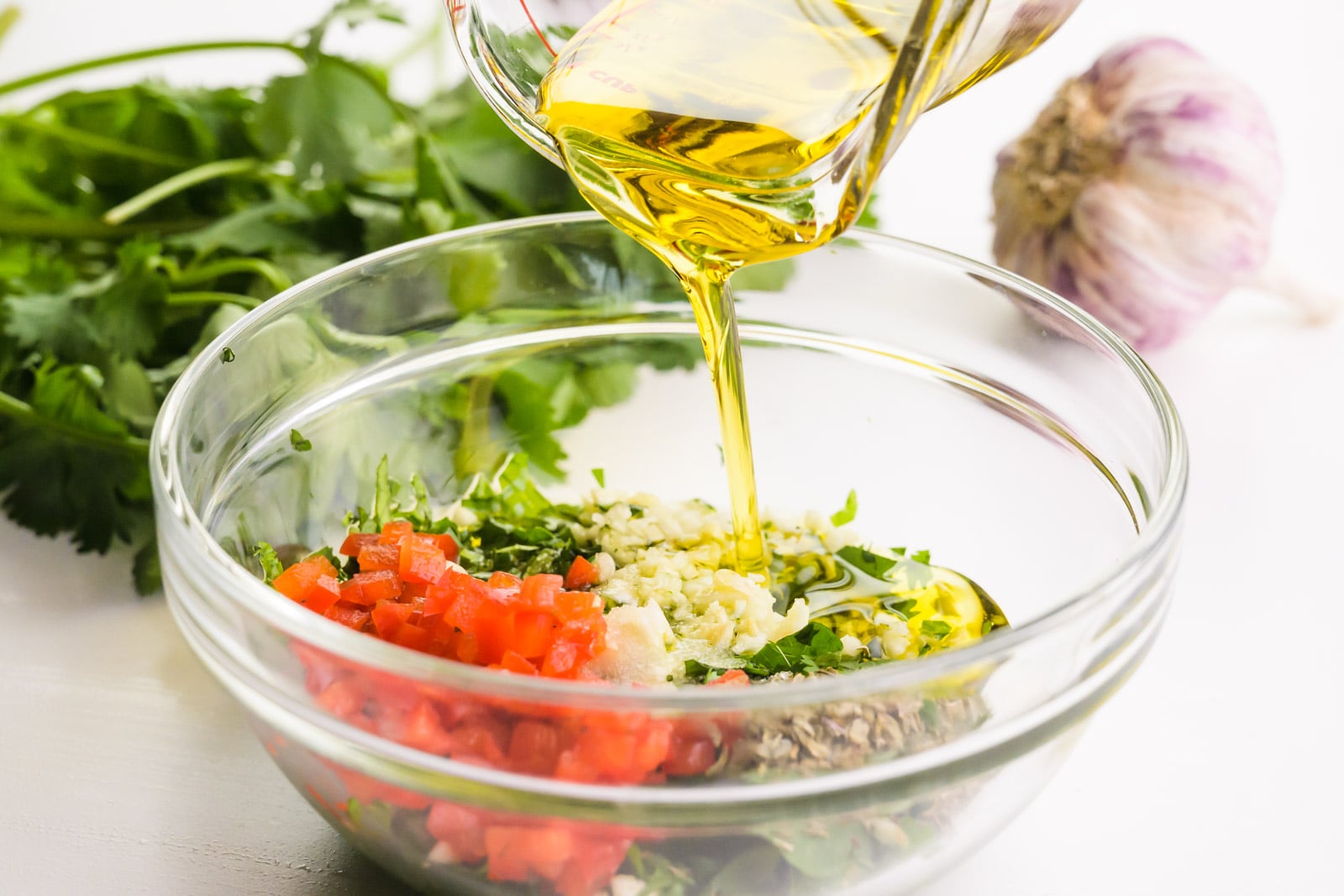 Oil is being poured into a bowl full of ingredients