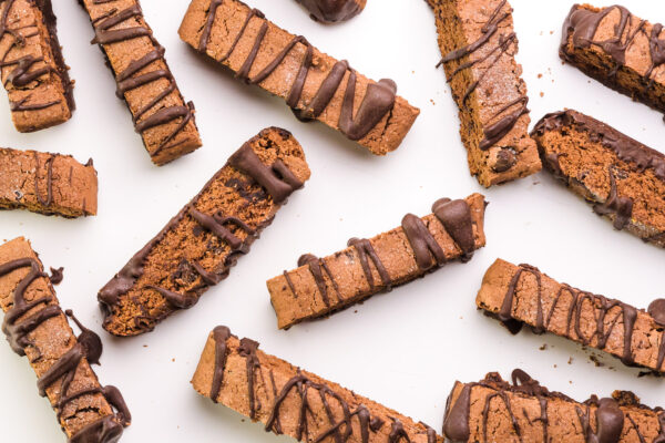Biscotti cookies have been drizzled in chocolate and set on a pan to dry.