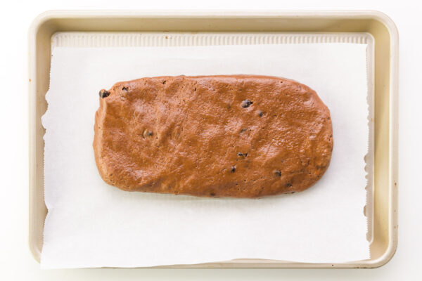 Looking down on a loaf of cookie batter shaped into a log on a baking pan.