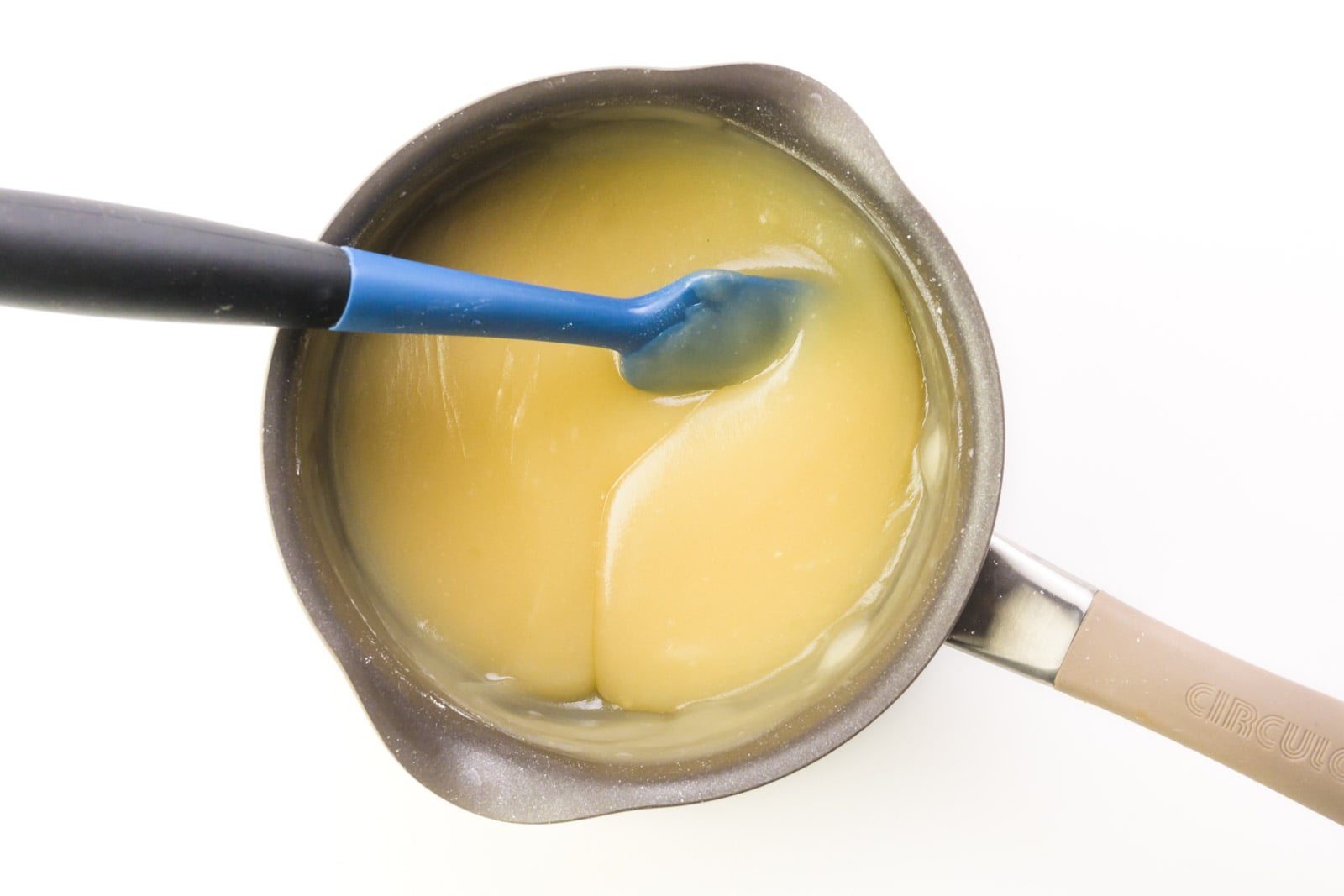 A creamy mixture is in a saucepan and a spatula has been run through the mixture, creating a line.