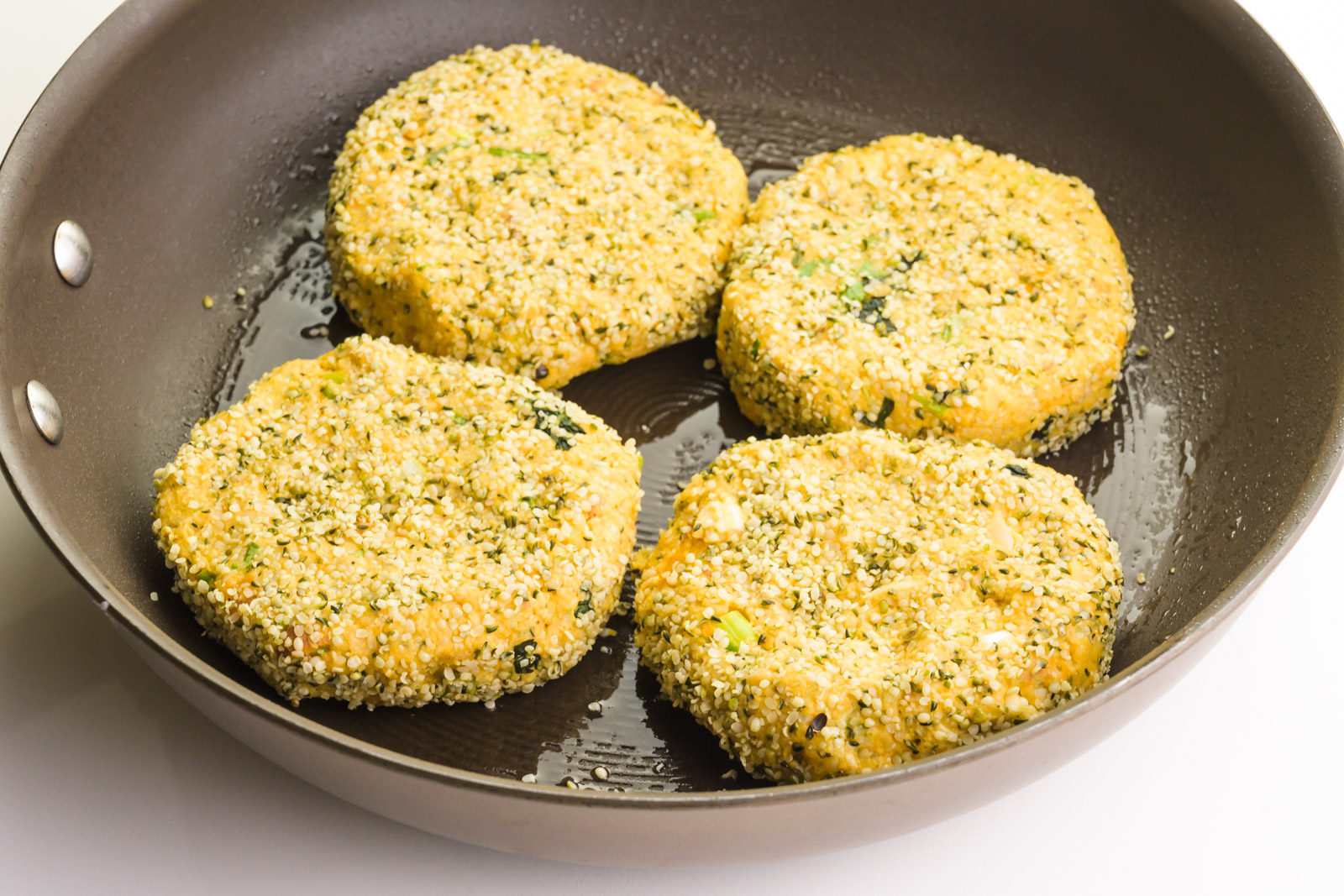 Veggie burgers are being cooked in a skillet.
