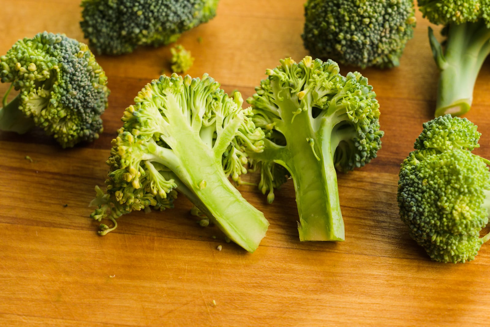 Broccoli has been cut into florets and one of the larger florets has been cut in half.