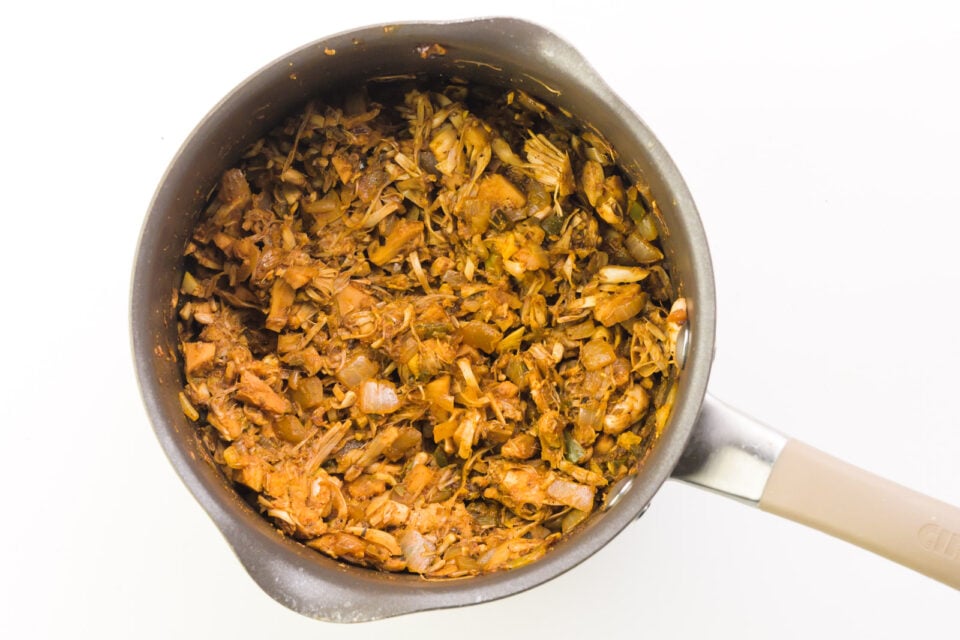 Looking down on a saucepan that holds jackfruit being cooked with spices.