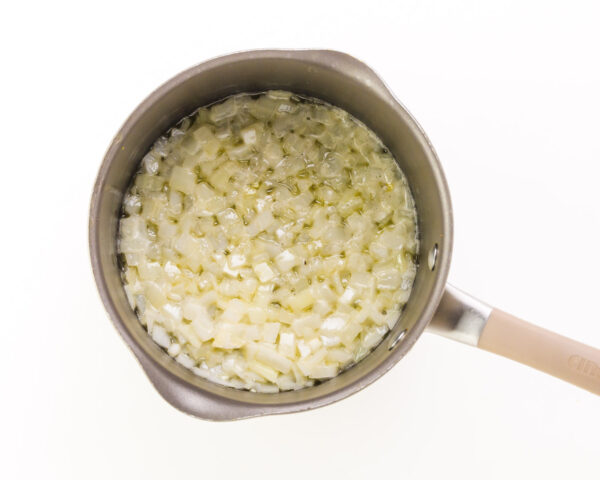 Onions are being cooked in the bottom of a saucepan.
