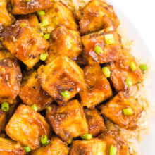 Looking down on a plate of orange tofu on a bed of rice.
