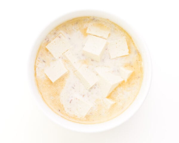 Looking down on tofu in a bowl with batter.