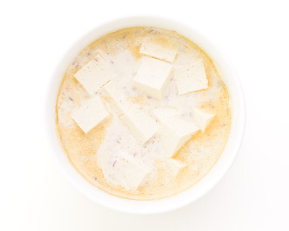 Looking down on tofu in a bowl with batter.